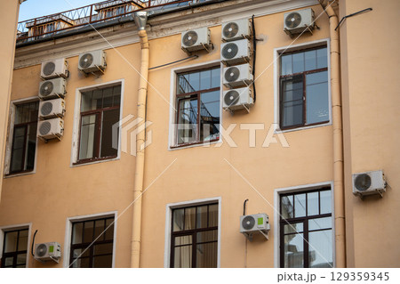 Facade of building with many air conditioners on windows in southern hot country. Escape from heat 129359345