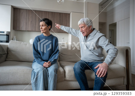 Angry hysterical elderly husband berating wife with gaslighting behavior, woman in fear on sofa 129359383
