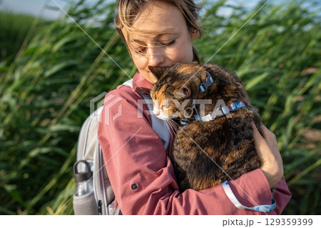 Sullen intrigued cat observing surroundings on walk clinging to woman in nature. Scared pet explorer 129359399