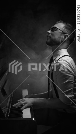 Pianist playing piano in smoky dramatic light with emotional expression Pianist playing piano in smoky dramatic light with emotional expression 129359745