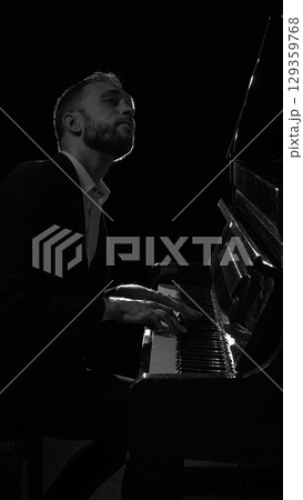 Male pianist playing piano in dark studio with emotional focus 129359768