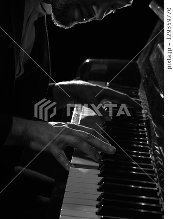 Close up of male pianist hands pressing piano keys in dramatic light 129359770