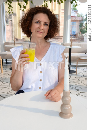 Woman enjoying a refreshing drink in a bright modern cafe 129361151