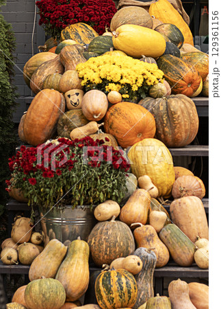 Autumn decor with pumpkins, gourds, and flowers displayed on outdoor steps 129361156