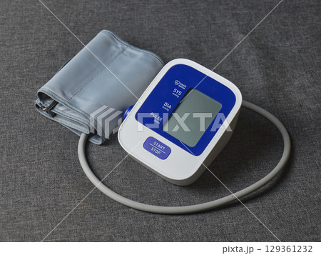 Digital blood pressure monitor and cuff laid out on a textured gray background. High quality photo Digital blood pressure monitor and cuff laid out on a textured gray background. High quality photo 129361232