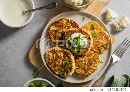Vegetarian cauliflower pancakes, fritters served with sour cream Vegetarian cauliflower pancakes, fritters served with sour cream 129361501