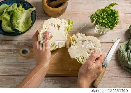 Female hands holding cauliflower lettuce halves, cooking healthy vegetables 129361509