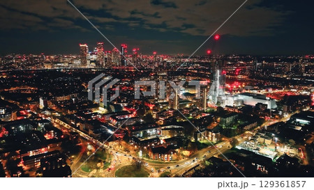 Breathtaking aerial view of London at night, highlighting the vibrant glow of Canary Wharf amidst a bustling urban landscape filled with illuminated buildings and dynamic energy. Drone flight Breathtaking aerial view of London at night, highlighting the vibrant glow of Canary Wharf amidst a bustling urban landscape filled with illuminated buildings and dynamic energy. Drone flight 129361857