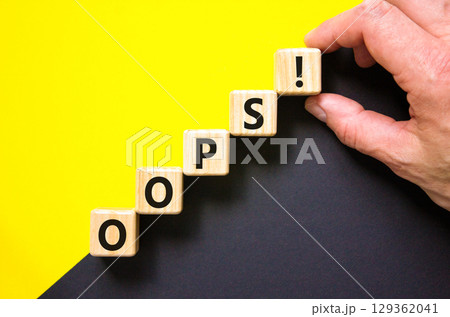 Oops symbol. Concept word Oops on beautiful wooden blocks. Beautiful yellow and black background. Businessman hand. Business lifestyle oops concept. Copy space. 129362041