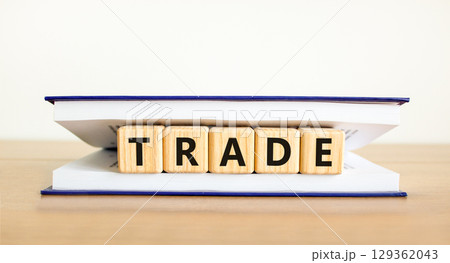 Trade symbol. Concept word Trade on beautiful wooden blocks in book. Beautiful wooden table white background. Business lifestyle trade concept. Copy space. Trade symbol. Concept word Trade on beautiful wooden blocks in book. Beautiful wooden table white background. Business lifestyle trade concept. Copy space. 129362043