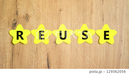 Reuse symbol. Concept word Reuse on beautiful yellow paper stars. Beautiful wooden table wooden background. Business lifestyle ecological reuse concept. Copy space. 129362056