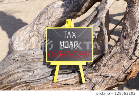 Tax year overview symbol. Concept words Tax year overview on beautiful black yellow blackboard. Beautiful old wood and sand background. Business tax year overview concept. Copy space. 129362102