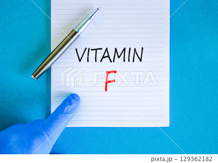 Vitamin F symbol. Concept words Vitamin F on beautiful white note. Doctor's hand in blue medical glove. Black pen. Beautiful blue background. Medical healthy lifestyle Vitamin F concept. 129362182