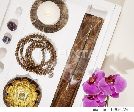 Self-care, healing flat lay with rosary beads, candles, aroma sticks, chakra stones and orchid flowers on a white wooden tray. Concept of me time, relaxing at home, energy healing and meditation Self-care, healing flat lay with rosary beads, candles, aroma sticks, chakra stones and orchid flowers on a white wooden tray. Concept of me time, relaxing at home, energy healing and meditation 129362269