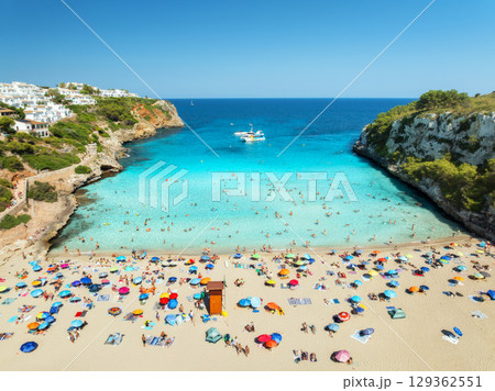 Aerial view of colorful umbrellas on sandy beach, swimming people 129362551