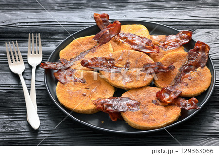 bacon pancakes drizzled with sirup on a plate 129363066