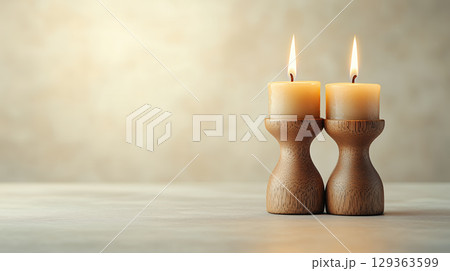 Two beige candles in rustic wooden holders create warm ambiance 129363599