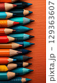 Vibrant colored pencils arranged on burnt orange background 129363607