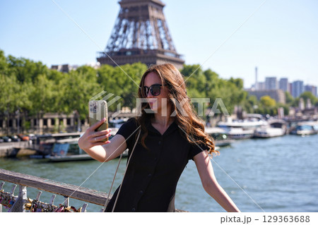Woman taking selfie on bridge with Eiffel Tower in Paris 129363688
