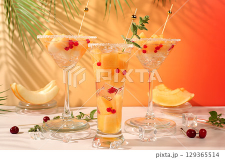 Melon alcoholic or non-alcoholic cocktail with mint. Martini, mojito and royal sangria with melon slices, ice, mint and currants. Summer party concept, advertising for a bar or cafe, detox diet Melon alcoholic or non-alcoholic cocktail with mint. Martini, mojito and royal sangria with melon slices, ice, mint and currants. Summer party concept, advertising for a bar or cafe, detox diet 129365514