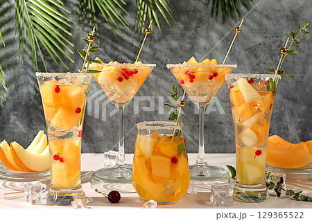 Melon alcoholic or non-alcoholic cocktail with mint. Martini, mojito and royal sangria with melon slices, ice, mint and currants. Summer party concept, advertising for a bar or cafe, detox diet Melon alcoholic or non-alcoholic cocktail with mint. Martini, mojito and royal sangria with melon slices, ice, mint and currants. Summer party concept, advertising for a bar or cafe, detox diet 129365522