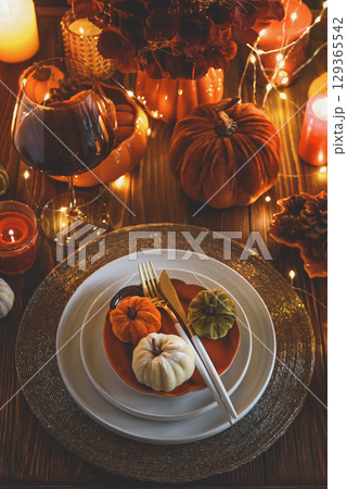 Autumnal table setting with decorative pumpkins, candles and string lights. Autumnal table setting with decorative pumpkins, candles and string lights. 129365542