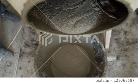 Construction worker pouring cement from mixer 129365587
