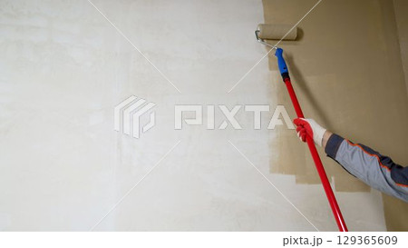 Painting walls with a roller. Painting a wall with a roller in yellow. 129365609