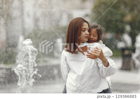 Family near the city fountain. Mother with gaughter playing with water. Family near the city fountain. Mother with gaughter playing with water. 129366883