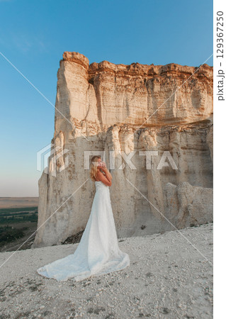 a woman in a white dress, a bride on a mountain with a blue sky. Beautiful nature, freedom, enjoyment of life. High quality photo 129367250