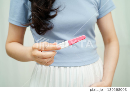 Asian holding pregnancy test for female of ovulation day, fetus, maternity, childbirth, birth control. Asian holding pregnancy test for female of ovulation day, fetus, maternity, childbirth, birth control. 129368008