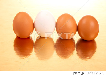 White and brown eggs lined up on a shiny golden background White and brown eggs lined up on a shiny golden background 129368179