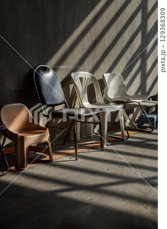 Morning sunlight shines through Wooden battens with hitting on Different five chairs in front of Old cement wall. Morning sunlight shines through Wooden battens with hitting on Different five chairs in front of Old cement wall. 129368309