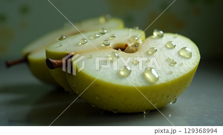 Macro photograph of sliced apple halves covered in translucent water droplets create a refreshing and vibrant image 129368994