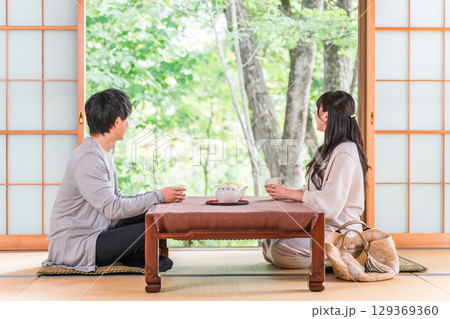 庭の景色が見える旅館の和室でお茶を飲むカップル,夫婦 129369360