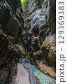 Narrow walkway carved into the cliffside along a turquoise stream inside Partnachklamm Gorge, Garmisch-Partenkirchen, Bavaria. A stunning natural passageway through dramatic alpine rock formations. 129369383