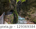 Narrow walkway carved into the cliffside along a turquoise stream inside Partnachklamm Gorge, Garmisch-Partenkirchen, Bavaria. A stunning natural passageway through dramatic alpine rock formations. 129369384