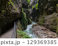 Narrow walkway carved into the cliffside along a turquoise stream inside Partnachklamm Gorge, Garmisch-Partenkirchen, Bavaria. A stunning natural passageway through dramatic alpine rock formations. 129369385