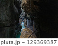Narrow walkway carved into the cliffside along a turquoise stream inside Partnachklamm Gorge, Garmisch-Partenkirchen, Bavaria. A stunning natural passageway through dramatic alpine rock formations. 129369387