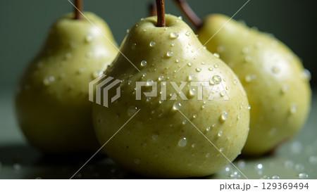 Captivating still life of three fresh green pears adorned with glistening water droplets revealing nature's beauty 129369494