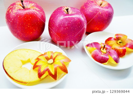 白バックに花の形に飾り切りされた林檎と輪切りで星形に型抜きされた赤い林檎 白バックに花の形に飾り切りされた林檎と輪切りで星形に型抜きされた赤い林檎 129369844