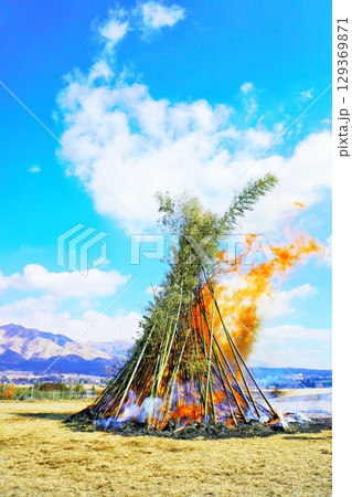 青空の下で正月飾りや書初めを燃やすとんど焼きの大きな櫓、豊作を願う日本の正月の風物詩 129369871