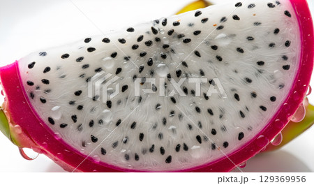 A close-up of a dragon fruit slice showcasing the vibrant colors and juicy texture with drops 129369956