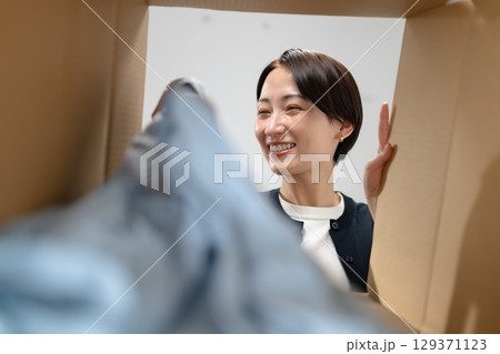 段ボールに服を入れる女性 段ボールに服を入れる女性 129371123