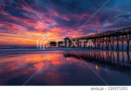 colorful sunrise over the beach with a pier. 129371201