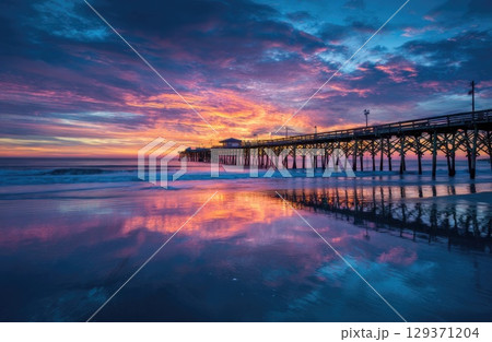 colorful sunrise over the beach with a pier. 129371204