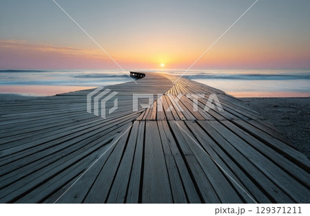 A long wooden bridge extends into the sea at sunset, symbolizing hope and future possibilities 129371211