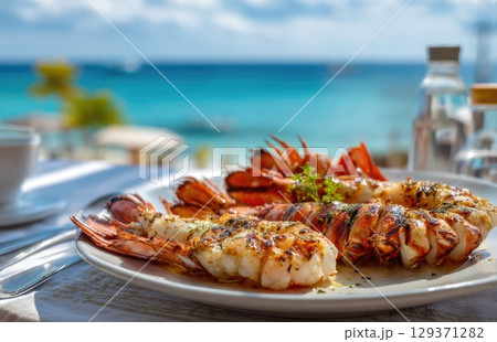 plate of fresh, grilled seafood with prawns and lobster on the beach in sunny Caribbean island 129371282