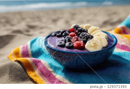 vibrant blue bowl filled with a purple smoothie, topped with banana slices and berries vibrant blue bowl filled with a purple smoothie, topped with banana slices and berries 129371393