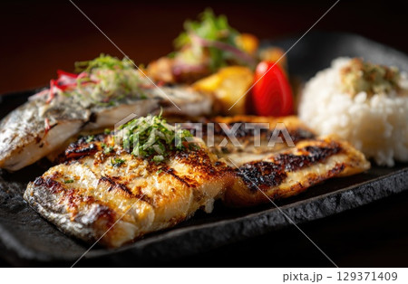 A plate of grilled mackerel with white rice, wasabi and pickled sonno sweeton inside the dish 129371409